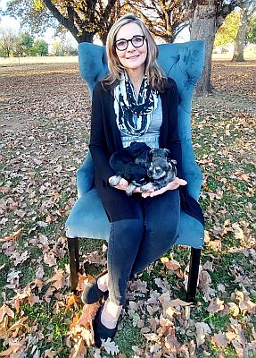 Dog breeder sitting on chair with puppies on lap