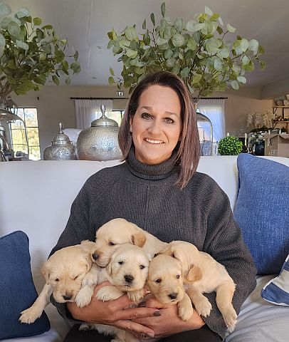 Breeder, seated, with an armful of puppies.